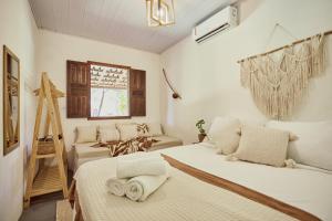 a bedroom with two beds and a couch at Vila Três - A apenas 2 minutos da praia! in Caraíva