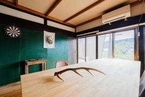 a large wooden table in a room with green walls at hinatabocco guesthouse in Miyaki +77 photos