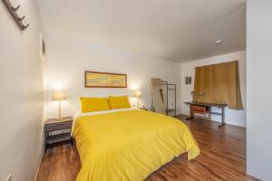ein Schlafzimmer mit einem gelben Bett und einem Schreibtisch in der Unterkunft Inventor's Cottage 30 Night Minimum home in Underwood