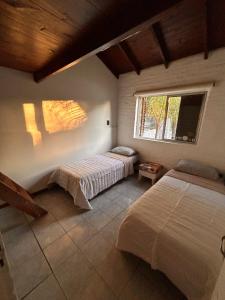 ein Schlafzimmer mit zwei Betten und zwei Fenstern in der Unterkunft Casa Barrio Los Sauces in Chascomús