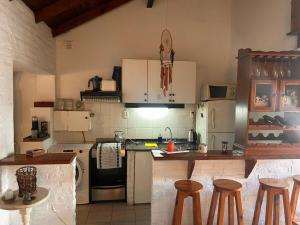 eine Küche mit einer Theke und einigen Hockern in der Unterkunft Casa Barrio Los Sauces in Chascomús