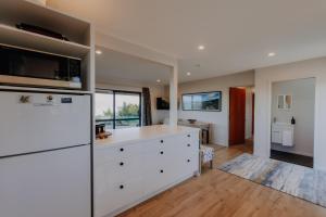 a kitchen with white cabinets and a refrigerator at Expansive Ocean & Mountain Views - KK82140 in Kaikoura