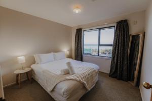 a bedroom with a bed and a large window at Expansive Ocean & Mountain Views - KK82140 in Kaikoura