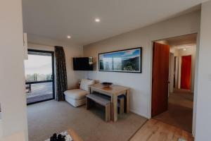 a room with a living room with a table and a chair at Expansive Ocean & Mountain Views - KK82140 in Kaikoura