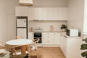 a white kitchen with a table and a white refrigerator at Salt Cottage in Port Fairy