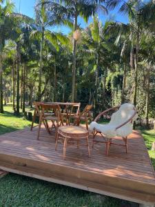eine Holzterrasse mit einem Tisch, Stühlen und Palmen in der Unterkunft Casa das Palmeiras in Orleans