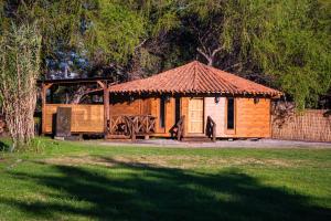a wooden gazebo in a park with a tree at Antu Wellness cabaña de lujo en paine in Maipo