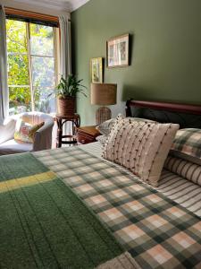 Un dormitorio con una cama y un sofá y una ventana. en Green Gables B&B Waterfront Apartment or Garden Studio, en Cygnet