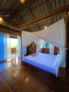 a bedroom with a white bed with a wooden floor at Lily's Blue View in Koh Rong Island