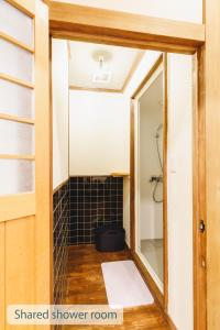 a bathroom with a mirror and a black tiled shower room at Couch Potato Hostel in Matsumoto