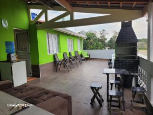 a patio with green walls and chairs and a fireplace at Pousada do Sossego Mar e verde 3 in Itanhaém