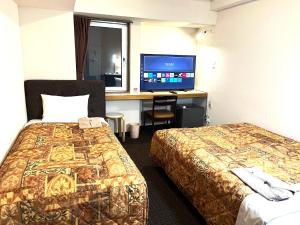 a hotel room with two beds and a desk with a tv at Hotel Tokeidai in Sapporo