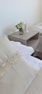 Cette chambre comprend des lits blancs et une table fleurie. dans l'établissement Departamento 25 de mayo Buenos Aires, à Veinticinco de Mayo