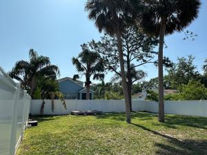 a backyard with a white fence and palm trees at CASA SOLÉ, South Tampa in Tampa