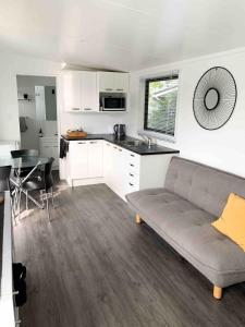 a living room with a couch and a kitchen at Tuia Retreat in Whangaparaoa