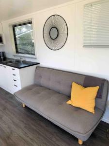 a couch with a yellow pillow in a kitchen at Tuia Retreat in Whangaparaoa