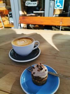 a cupcake on a plate next to a cup of coffee at Tuia Retreat in Whangaparaoa