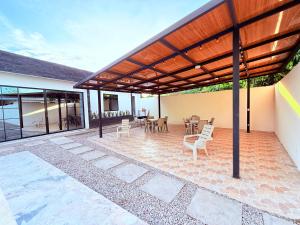a patio with a wooden pergola and tables and chairs at Villa Santy Paraiso lujoso & Privado in Ricaurte