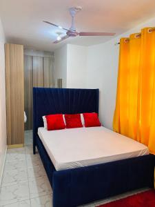 1 cama con 2 almohadas rojas en una habitación en Home by Mercy Apiyo, en Mombasa