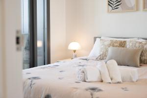 a bedroom with a white bed with towels on it at Chic Woden Apt, Near Hospital, Westfield w Pool in Phillip +20 photos