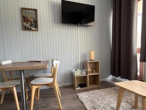a living room with a table and a television on the wall at Studio moderne à Super Besse, vue lac des Hermines - FR-1-814-136 in Super Besse