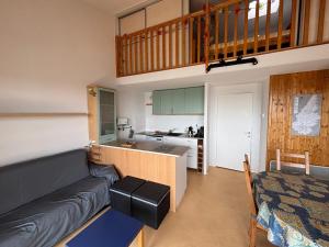Una sala de estar con un sofá y una cocina. en L'INTEMPOREL RESIDENCE LES HERMINES APPARTEMENT POUR 8 PERSONNES - FR-1-814-148, en Super Besse