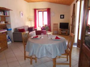 un soggiorno con un tavolo e un divano di Gîte rural confortable avec terrasse, proche de Roanne - FR-1-496-376 a Vendranges