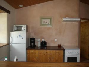 una cucina con un frigorifero bianco e una stufa di Gîte rural confortable avec terrasse, proche de Roanne - FR-1-496-376 a Vendranges