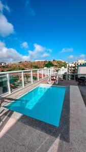 a blue swimming pool on top of a building at Hospedatom - Cobertura Vista Mar com Piscina Arraial do Cabo in Arraial do Cabo