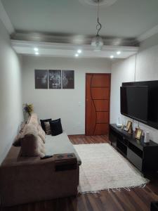 a living room with a couch and a flat screen tv at Aconchegante Apartamento em Ouro Preto in Ouro Preto