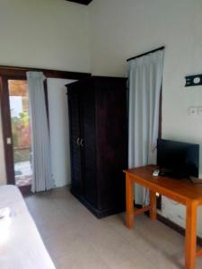 una habitación con una cama y un escritorio con una computadora en Green Bowl Bali Guest house, en Ungasan