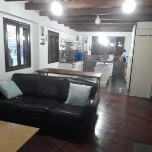 a living room with a black couch and a kitchen at casa Montisora in Baños