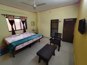 戴维格Shri Samarth Homestay的一间带床、椅子和电视的卧室