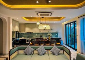 a living room with a couch and a kitchen at Hometown Signature Retreat Villa Hoi An in An Bang