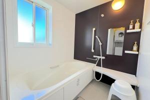 a white bathroom with a tub and a window at Grande Ortho Okinawa Villa Onna 3 - Vacation STAY 91376 in Onna +37 photos