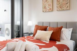 a bedroom with a bed with orange and white pillows at Cosy Woden Apt Near Canberra Hospital,Transport in Phillip +24 photos