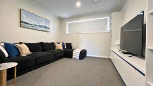 a living room with a black couch and a flat screen tv at La Dolce Vita in Sussex inlet