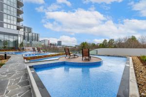 a pool with two chairs in a building at Cosy Woden Apt Near Canberra Hospital,Transport in Phillip