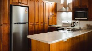 a kitchen with a stainless steel refrigerator and wooden cabinets at Riverfront Retreat Sussex House Park in Sussex inlet