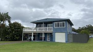 a blue house with a balcony and a yard at Greentree Sanctuary In South Sussex in Sussex inlet