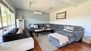a living room with a blue couch and a table at Greentree Sanctuary In South Sussex in Sussex inlet