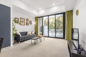 ein Wohnzimmer mit Sofa und Fernseher in der Unterkunft Bright Lyneham Hideaway, Gym, Free Parking, ANU in Downer