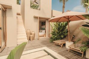 Cette maison dispose d'une terrasse avec un parasol et des chaises. dans l'établissement NORI Boutique Villas, Near Nyang Nyang Beach, Uluwatu, à Uluwatu