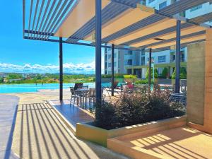 a patio with a table and chairs under a pergola at Lumpini Park Beach Jomtien & Seaside Condo in Jomtien Beach