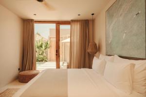 une chambre avec un lit avec une grande fenêtre dans l'établissement NORI Boutique Villas, Near Nyang Nyang Beach, Uluwatu, à Uluwatu