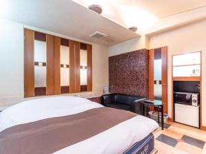 a bedroom with a large bed and a black chair at Tabist HOTEL SWEETWATER in Takamatsu