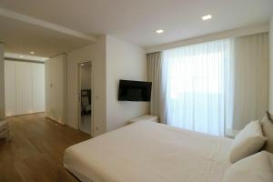 a bedroom with a white bed and a television at Modern Villa With Views Of Ortigia in Carrozziere – Fonte Ciane