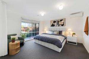 a bedroom with a bed and a chair and a window at Family Oasis near Watergardens Parking in Sydenham