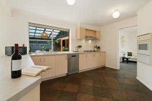 a kitchen with white cabinets and a bottle of wine at Family Oasis near Watergardens Parking in Sydenham