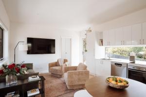 a kitchen and living room with a bowl of fruit on a table at The Bennett Loft, a modern Launceston hideaway in Kings Meadows
